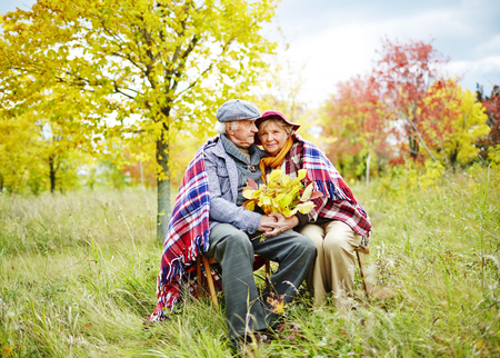 45115567 - old man and woman in warm clothes sitting in park at leisure